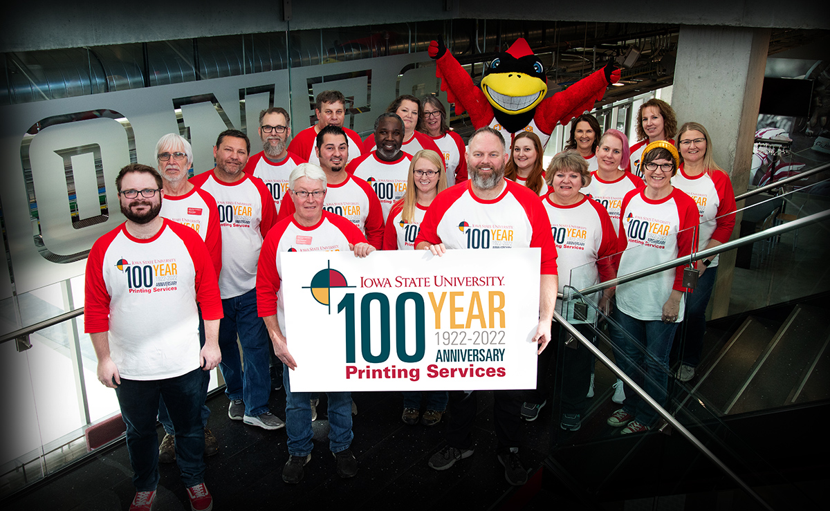 Printing Services employees standing in a group with matching shirts. Celebrating 100 years at ISU.